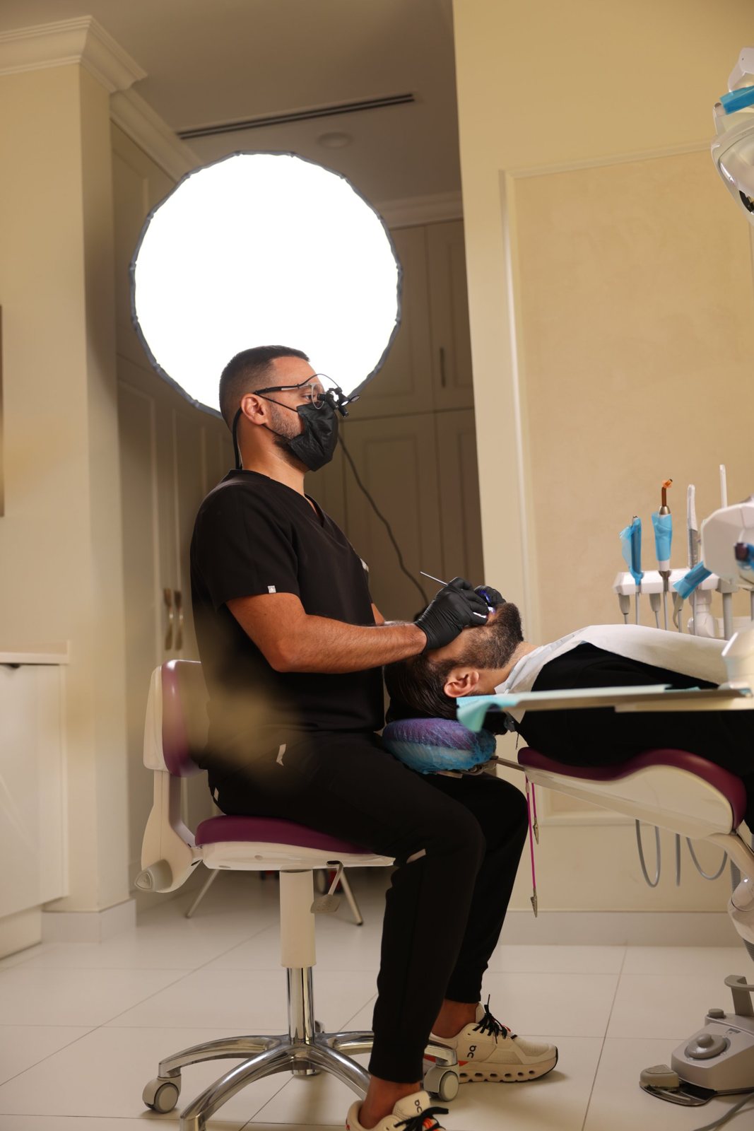 Side view of a dentist with loupes treating a reclined patient in a Creative Arts surgery, Dubai